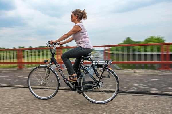 Vrouw fiets op een e-bike over de weg.