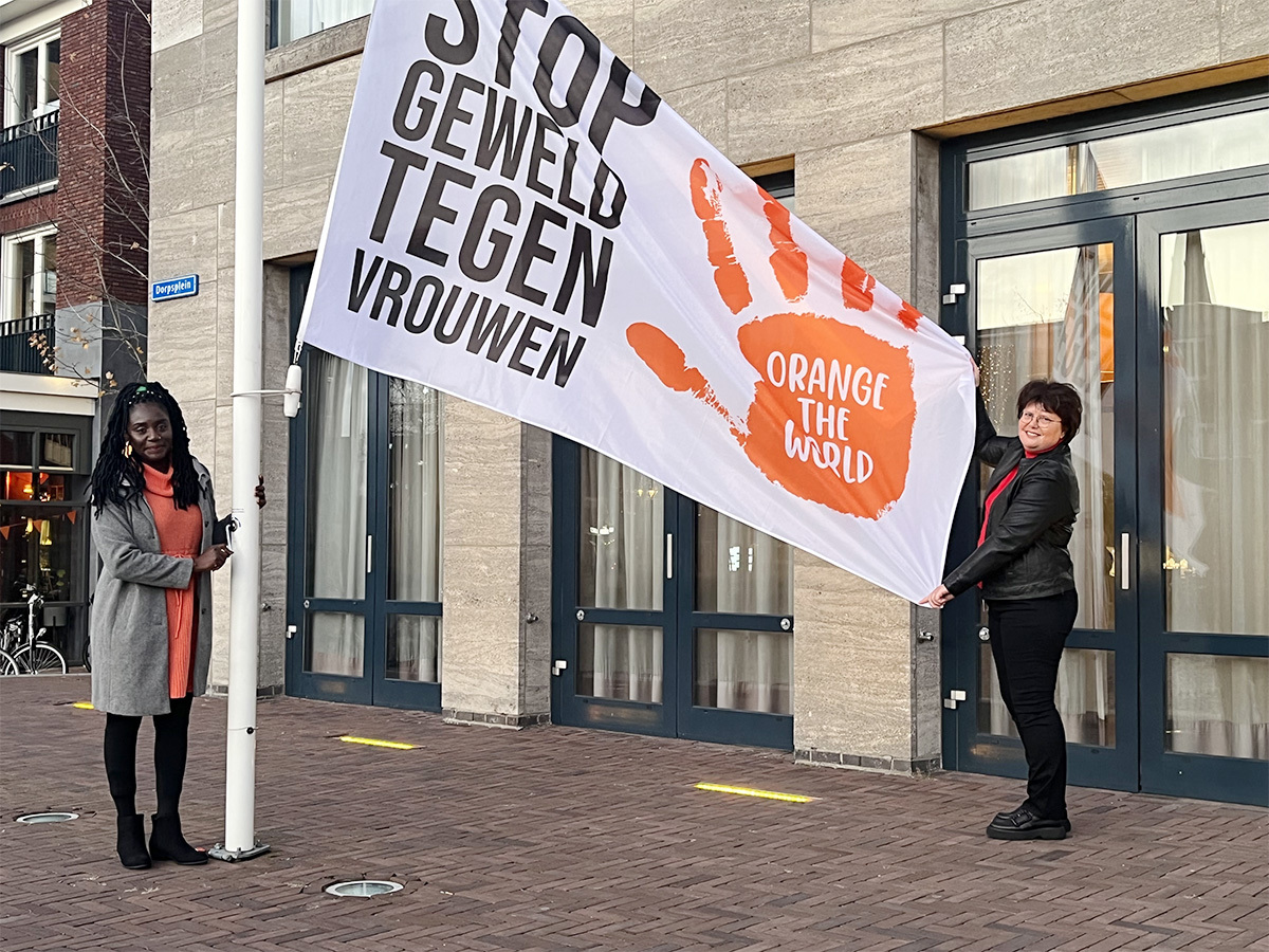 Wethouder Veronique Zeeman en Ama een oud-bewoner Blijf van mijn Lijfhuis hijsen de vlag van Orange the World