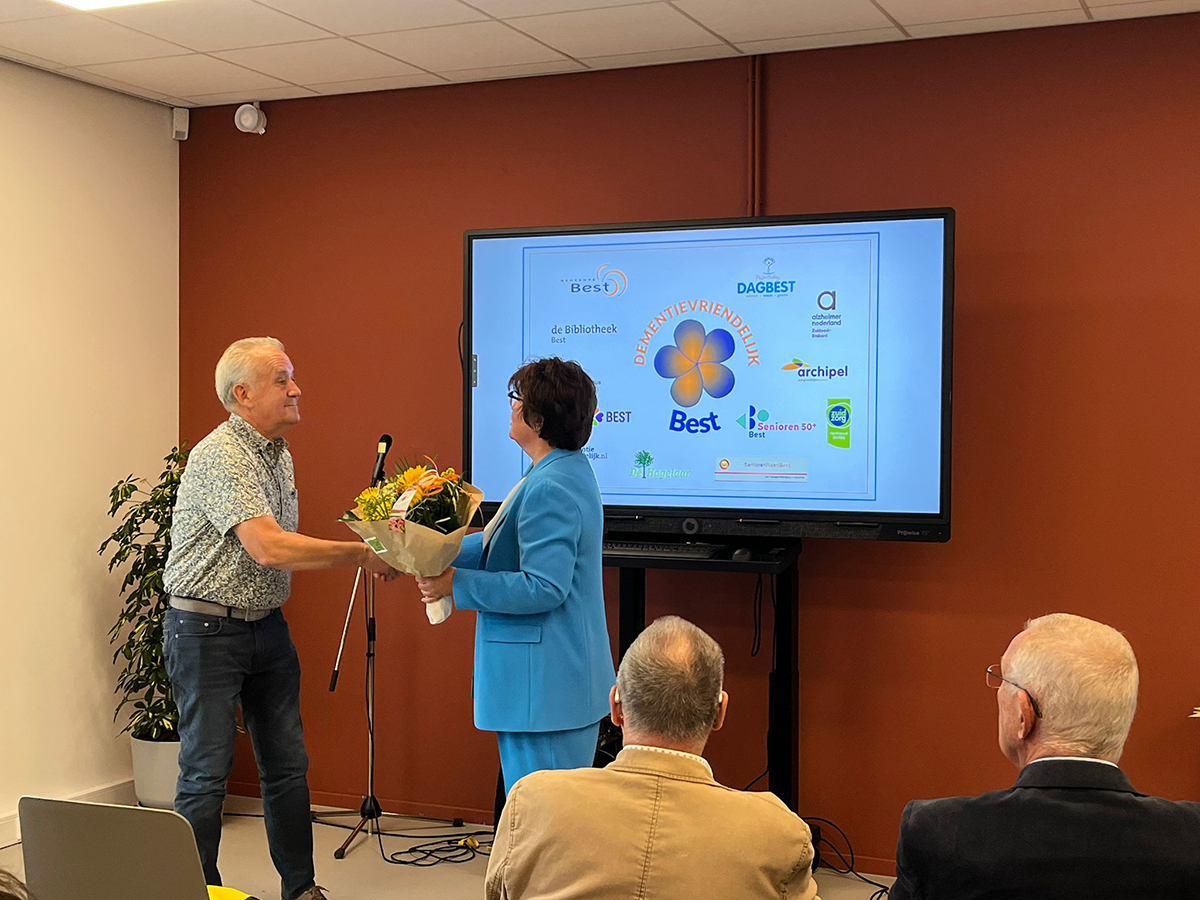 Wethouder Zeeman neemt het certificaat en een bloemetje in ontvangst.