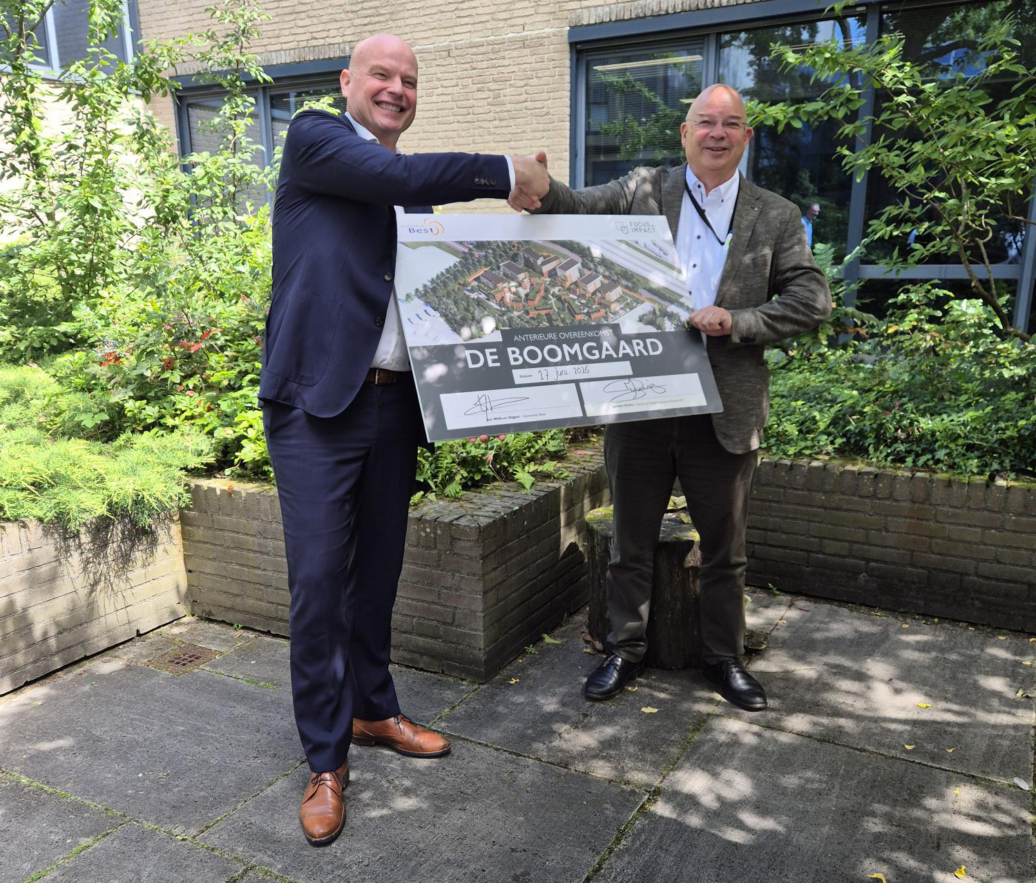 Jeroen Smits van Focus on Impact en rechts wethouder Jan Willem Slijper poseren met de handtekeningen op een Boomgaard-bord.